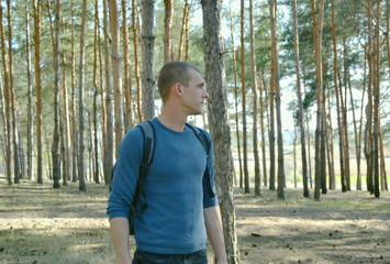 young man with backpack walking in the woods