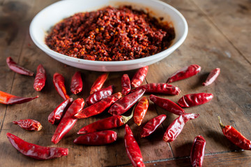 Dried chilies and chili sauce are on the wooden table