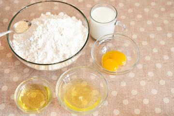 the process of making dough for pancakes with ingredients on a light table, eggs and flour are whipped with a mixer