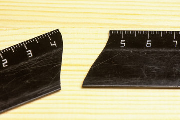 Used and broken plastic black ruler on a wooden background. There are a lot of scratches on the...
