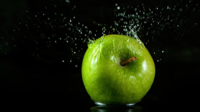 Super Slow Motion Shot of Fresh Green Apple Falling into Water Isolated on Black Background at 1000fps.