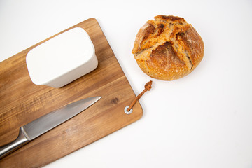 Flat lay packshot chleb z deską, nożem i maselniczką bochenek domowego pieczywa na dużej desce do krojenia
