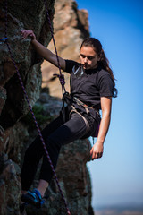 Naklejka premium Young woman beginner climbing vertical cliff