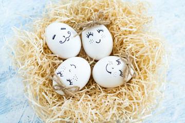 white Easter eggs with cute emotions in a nest on a light background in rustic style