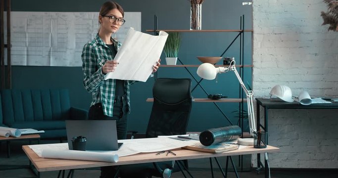 Architect drawing blueprints in office. Engineer sketching a construction project. Architectural plan. Portrait of beautiful woman concentrated on work. Business construction concept.