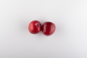 Juicy red plums with leaves, isolated on white background.