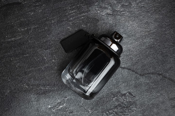 Bottle of men's perfume  on a black stone background. Fashion concept.
