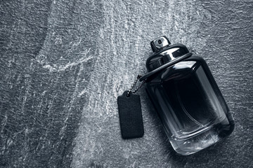 Bottle of men's perfume  on a black stone background. Fashion concept.