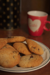A plate of cookies next to a red cup of coffee with a heart