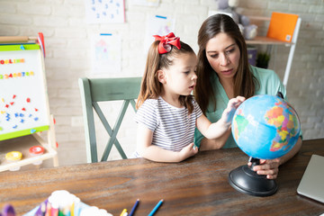 Mother homeschooling daughter with globe