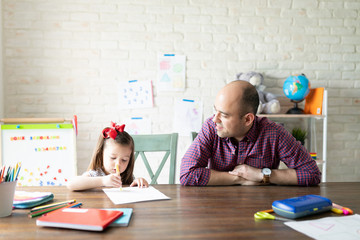 Dad tutoring his daughter at homeschool