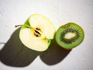 Halves of kiwi, apple on a white background with shadows. Summer concept.