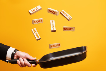 budget planning concept. a man in a pan throws wooden blocks with the words investment, profit, incomes, taxes, cost, expenses