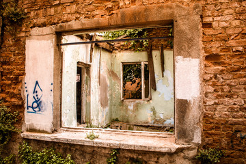 Fototapeta na wymiar inside view from the window of an abandoned tumbledown house, uninhabitable condition, build with refractory clay firebricks, stays with very old wooden frames