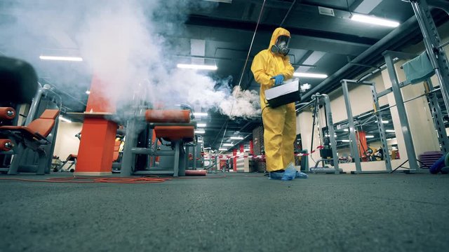 Sanitary worker is fumigating chemicals in the gym