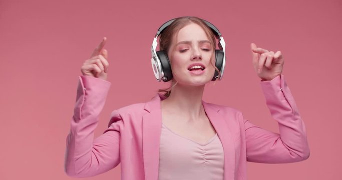Happy Girl using Headphones, starting to dance while Listening to Music. Beautiful Girl dancing on Studio in big Headphones, having Fun. Music Applications. Good Music. Music Lovers.