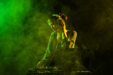 girl dj playing music with a mixer, yellow and green smoke in the background