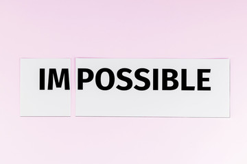 Word "impossible", written on paper, is cut into two halves. Made out of impossible - possible.
