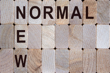 Wooden blocks form the words 'new normal'. Beautiful wooden background.