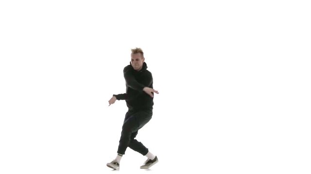young handsome guy in black tracksuit vigorously dancing hip hop, freestyle, street dance, performs complex movements, isolated, slow motion