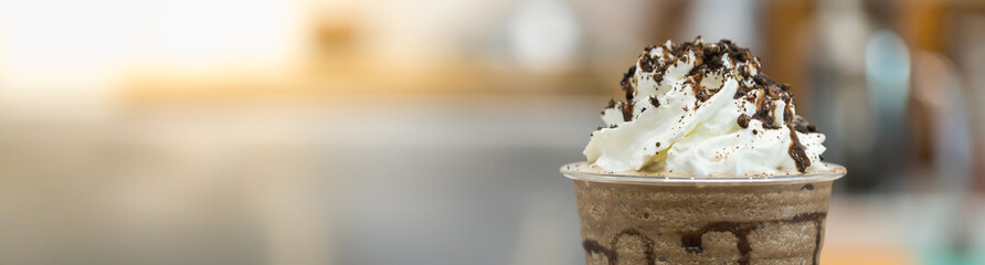 Closeup of takeaway plastic cup of coffee mocca frappe with whipped cream and chocolate sauce and chips with copy space. Using for cover page.