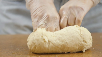 woman mother or daughter on the kitchen table makes domestic food pizza, hands work and pushing stir knead the dough, selective focus dolly shot