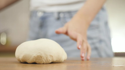 woman on the kitchen table makes domestic food pizza, hands work and pushing stir knead the dough, selective focus dolly shot
