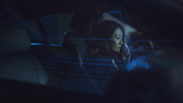 A Woman Sits In A Car At Night And Speaks On The Phone