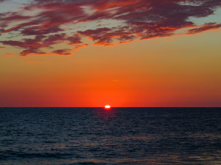 Red sky caused by stunning sunset at sea in Mazatlan, Mexico