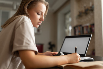 the girl does work from home, checks information from the phone and makes notes in the notebook during quarantine. Home workplace