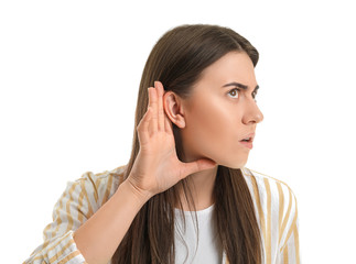 Young woman trying to hear something on white background