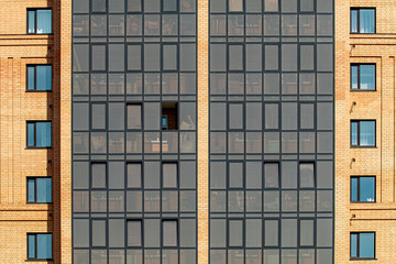Wall of a high-rise new brick building with windows, background.