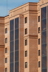 Fototapeta na wymiar Wall of a high-rise new brick building with windows, background.