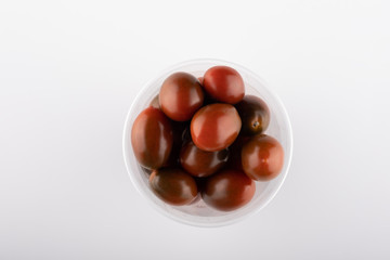 multi-colored tomatoes in a plastic box close-up on a white background