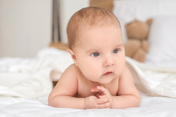 Cute little baby with towel lying on bed at home