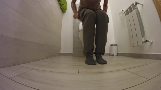 Woman peeing using toilet bowl wearing home clothes. Low angle shot of girl on her pyjamas urinates.