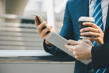 Close up of young businesswomen and smart business man with smartphone and coffee cup in hand