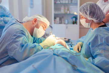 The surgeon leaned over the patient during the operation. A group of surgeons works in the operating room