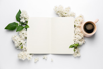 Obraz na płótnie Canvas Notebook, beautiful lilac flowers and cup of coffee on white background