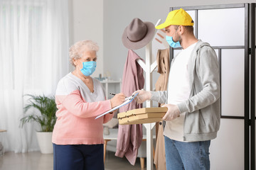 Senior woman receiving food from courier at home. Concept of epidemic