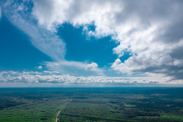 A dramatic blue sky with clouds over endless forest expanses. Aerial view