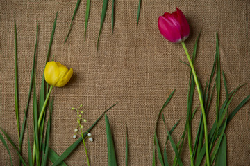 tap and yellow tulips lie on a rough cloth