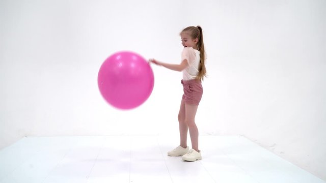 Little girl plays with a big ball for fitness