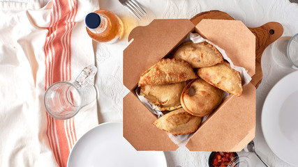 traditional argentinean empanadas in a box on a family table