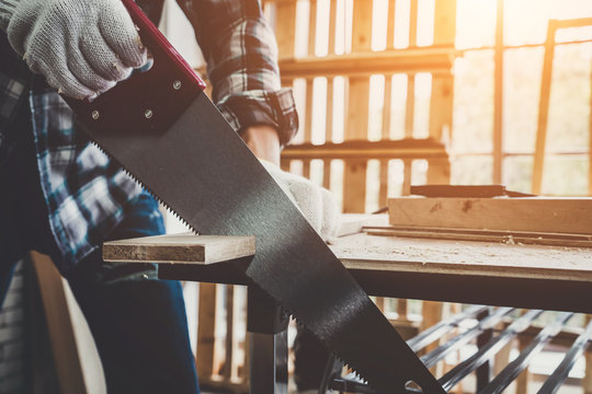 Carpenter working on wood craft at workshop to produce construction material or wooden furniture. The young Asian carpenter use professional tools for crafting. DIY maker and carpentry work concept.