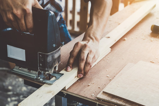 Carpenter working on wood craft at workshop to produce construction material or wooden furniture. The young Asian carpenter use professional tools for crafting. DIY maker and carpentry work concept.