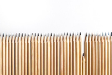 Row of even sharpened pencils made of wood stand next to each other