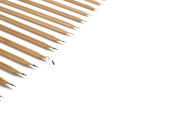Side view of row of even beautiful sharpened pencils lying on white table