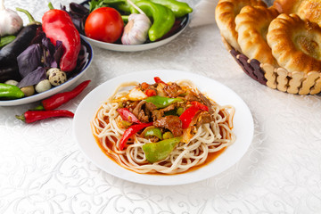 Dish with meat, noodles and vegetables. Traditional oriental dish. On a plate on a table in a restaurant.
