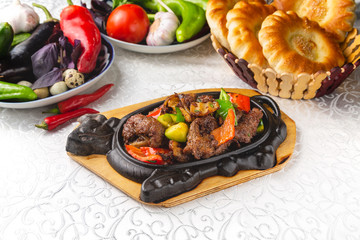 Roasted meat with red and green bell peppers. Traditional oriental dish. On a plate on a table in a restaurant.